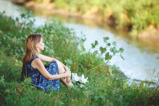 The girl sitting in front of a river after Headache Relief